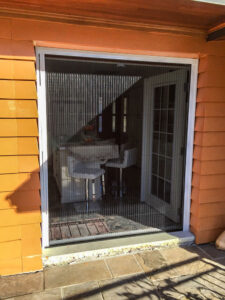 Vista One - Foldaway Screen large double door opening from kitchen to stone patio.